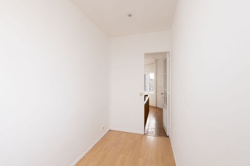 An empty room with a wooden floor and white walls is presented in the image