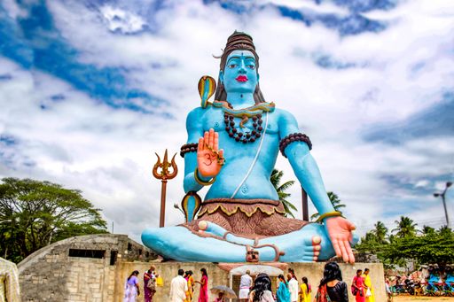 A view of a big statue of lord shiva under the cloudy sky
