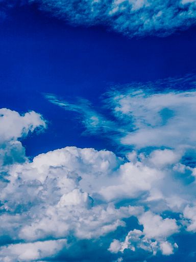 A vertical shot of white fluffy clouds on a blue sky - perfect for wallpaper