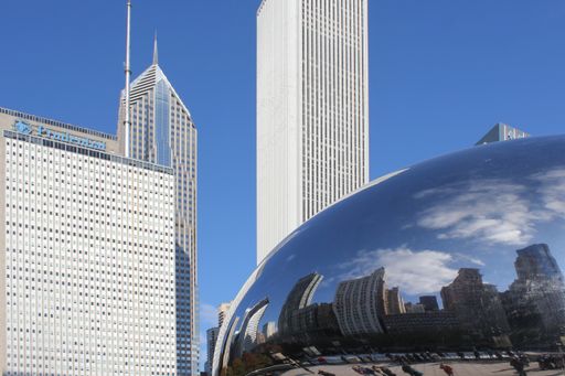 A close-up of British sculptor Anish Kapoor's 'Cloud Gate' in Millennium Park, Chicago. The skyline of Michigan Avenue is behind