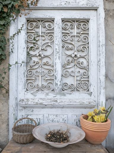 A vertical shot of an old decorative antique door with basket and flower pots bel