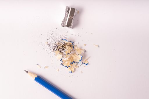 A top view of a blue pencil with metal sharpener and shavings isolated on a white background