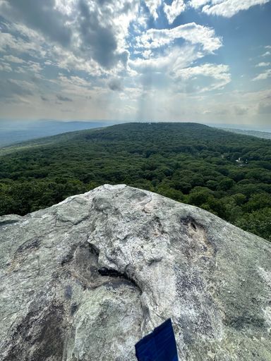 A vertical of a rocky outcropping against a green landscape