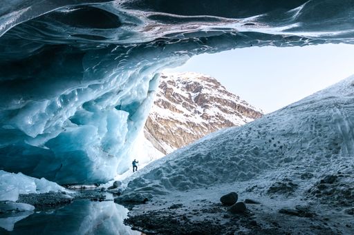 Silhouette of a hiker at the entrance of an ice cave in Zinal glacier in winter, Valais Switzerland