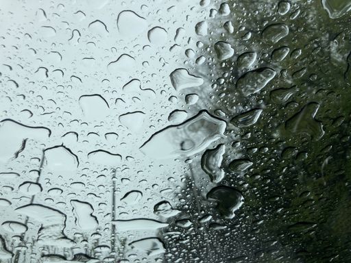 A closeup shot of large raindrops on a front window of a car