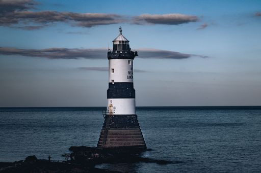 An idyllic Penmon lighthouse on a pier overlooking water in Anglesey, Wales