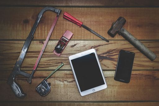 A display of hand tools on a wooden surface and a tablet and smartphone with space for your text