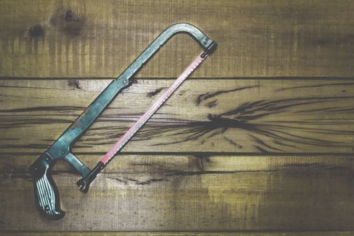 A top view shot of a hacksaw on a wooden table with a space for your text