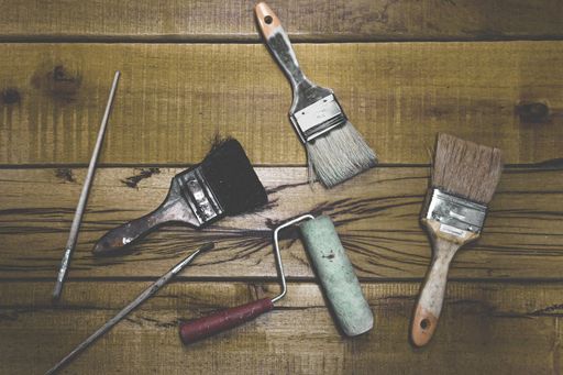 A top view shot of different painting materials on a wooden workbench