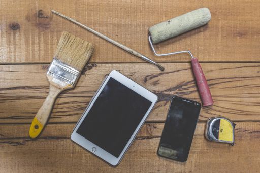A top view shot of painting tools on a workbench and a tablet and smartphone with space for your text