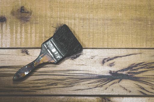A top view shot of a paintbrush on a wooden workbench with space for your text