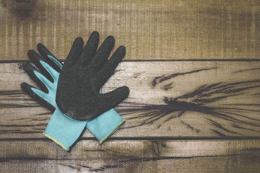 A closeup shot of black and blue working gloves on a wooden workbench with space for your text