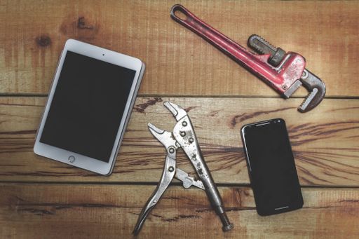 A top view shot wrenches, a black tablet and smartphone on  work bench with space for your text
