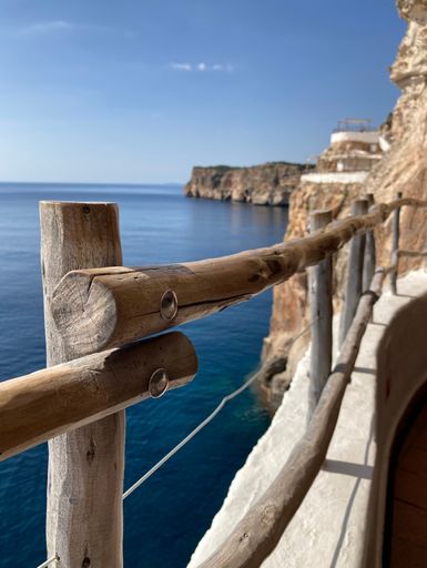 A vertical shot of a wooden railing over the shore of the Balearic Islands, Spain