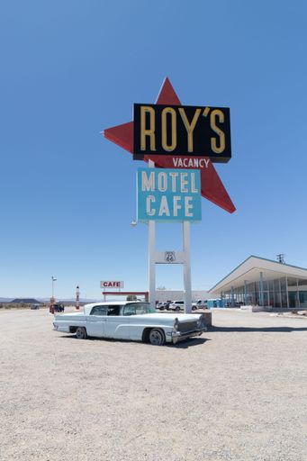 A retro car parked near the sign of Roy's Motel cafe