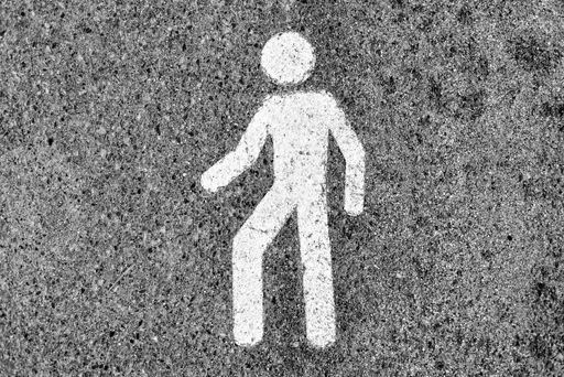 A top view shot of a white pedestrian sign on a concrete road