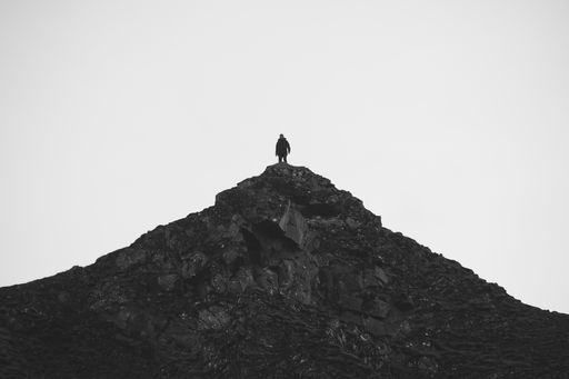 A silhouette of a man on top of a rocky mountain
