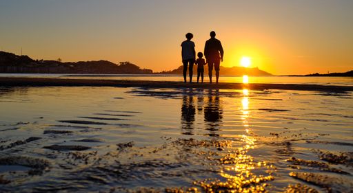 A silhouette of a family standing on the beach during sunset in Bayona, Galicia, Spain
