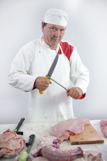 A vertical shot of a butcher cutting meat on the table