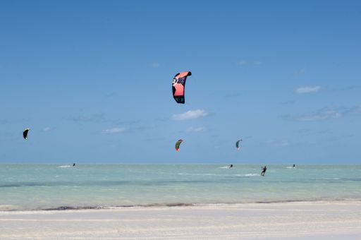 Kite surfing from the tropical beach of Holbox Island in Mexico, during low tide. In the background the Caribbean ocean and the blue sky