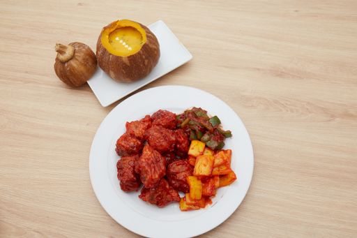 A top view of a meal cooked with green and yellow peppers and a pumpkin served on a white plate