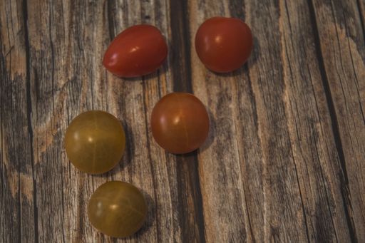 A high angle shot of raw and ripe cherry tomatoes on a wooden surface