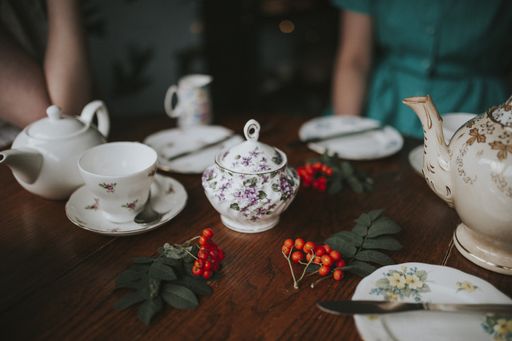 A closeup shot of a white floral tea set on brown wooden table