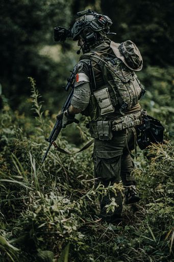 A soldier in camouflage with a rifle and helmet walking in the forest in Kharkiv, Ukraine.