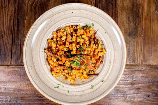 Close up shot of pasta with octopus and red sauce, wooden background, top view