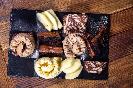 An overhead closeup shot of chocolate and vanilla ice cream scoops with slices of cake on the side