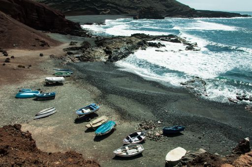 A beautiful bay with black volcanic sand and small fisher boats on Lanzarote.