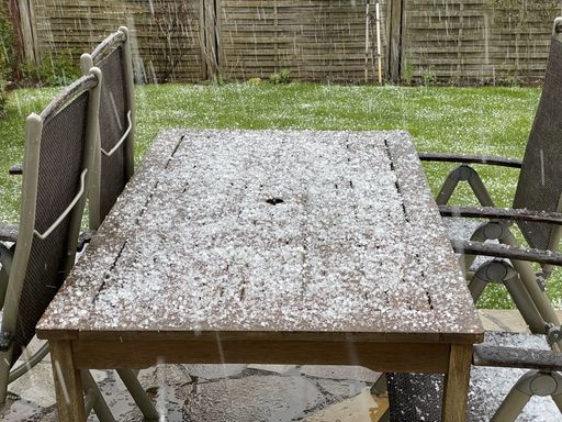 A closeup shot of a wooden table and chairs outdoors under hail