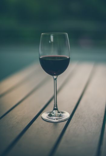 A vertical shot of a glass of wine on a wooden surface