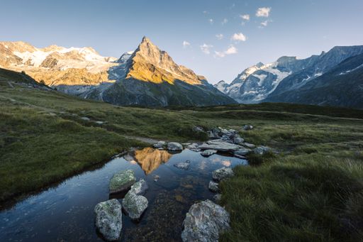 Summer landscape view in Zinal with the Besso mountain relecting in a stream at sunset