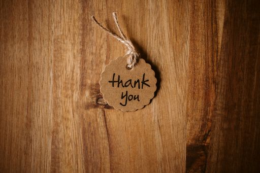 Thank you word written in a card on wooden background with selective focus. Love and gratitude concept.