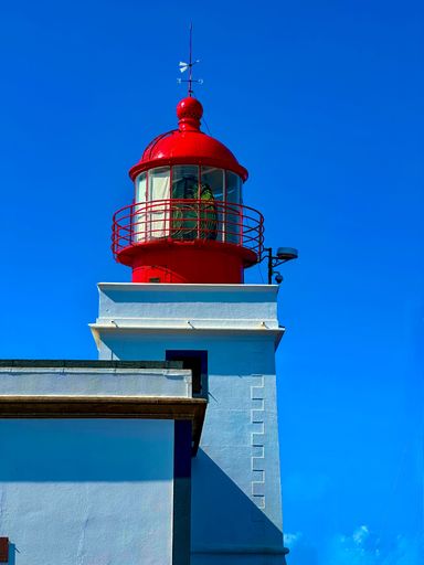 A lighthouse painted in red and white stands tall on Madeira's western cliffs