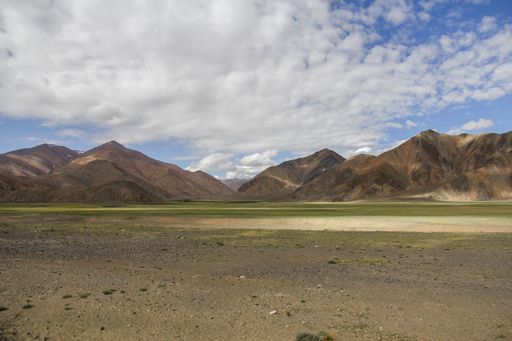 This stock photo depicts a sweeping expanse of desert terrain, with a large, expansive field of sand and rock stretching out towards the horizon
