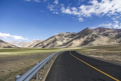 A picturesque, long, winding, and empty country road situated in the majestic mountain range