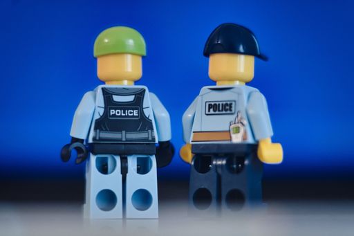 Lego figure of a police officer standing in front of blue background. Police and justice system concept