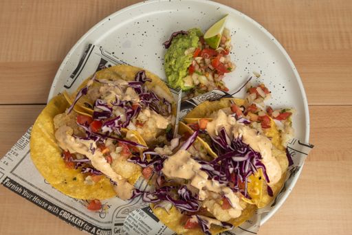 A top view of traditional Mexican tacos with meat and vegetables on wooden table