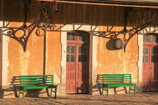 A side view of two wooden park benches situated close together in front of a brick building