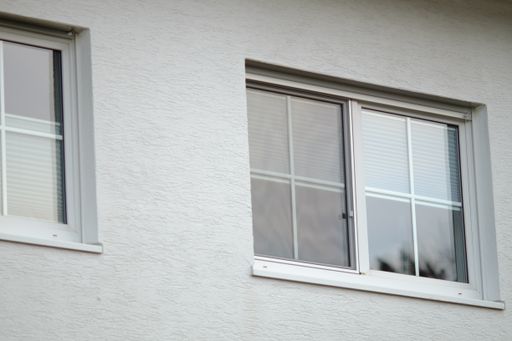 A low angle shot of a white building with two windows