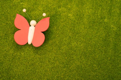 A top view shot of a wooden butterfly on the green grass as a garden decoration
