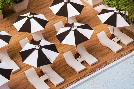 A high angle shot of a tranquil poolside paradise in Krabi, Thailand with black white umbrellas and chairs