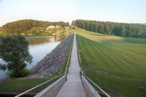 A narrow footpath between the lake and green agricultural field against the clear sky