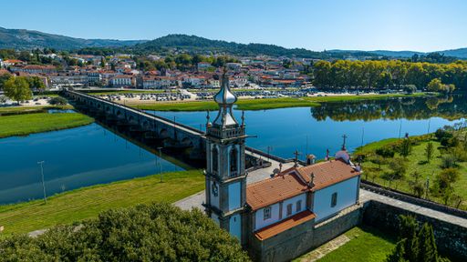 A stunning view of a picturesque town featuring a traditional church and a tranquil river surrounded by lush greenery