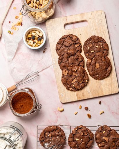 A flatlay shot of chocolate cookies, cocoa powder, and a bowl of peas on a table