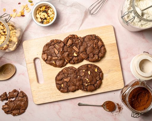 A flatlay shot of chocolate cookies, cocoa powder, and a bowl of peas on a table