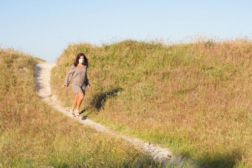 An excited female in a facial mask going down the hill path - a new normal concept