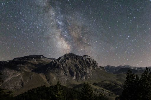 A stunning night sky featuring an array of twinkling stars and a majestic mountain range in the background